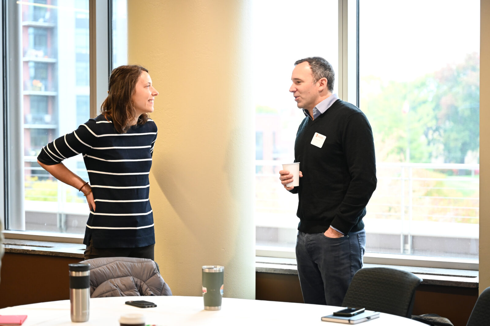 Two individuals are facing each other and talking while standing.