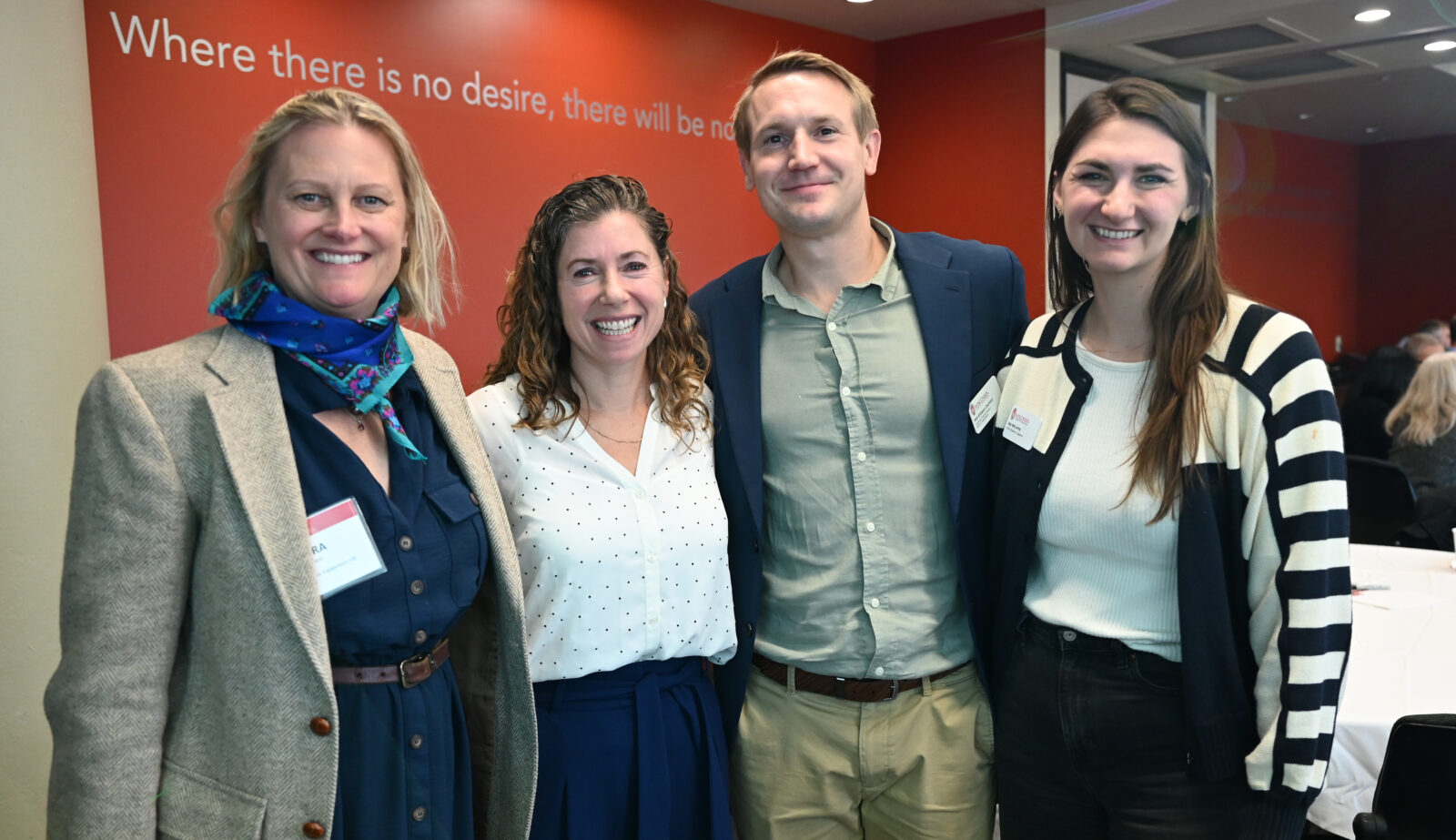 Four people stand together, posed for a photo.